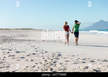 Jeune couple marchant sur le sable Banque D'Images