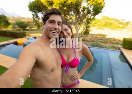 Un couple jeune et heureux se détendant près de la piscine Banque D'Images