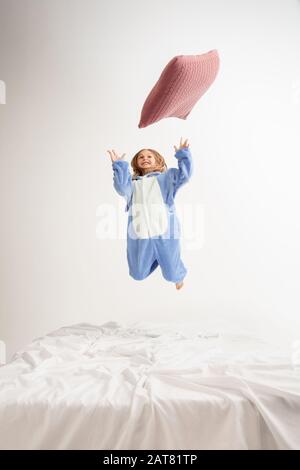 Petite fille dans un pyjama doux et chaud coloré lumineux jouant à la maison. Modèle mignon ayant plaisir, fête, rire, jouer, look élégant et heureux. Concept d'enfance, activité de loisirs, bonheur. Banque D'Images