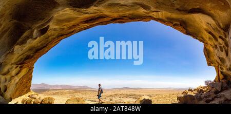 Vue panoramique depuis une grotte de Blutkuppe au-dessus du désert du parc Namib Naukluft, un homme marchant sous le dôme rocheux, Namibie, Afrique Banque D'Images