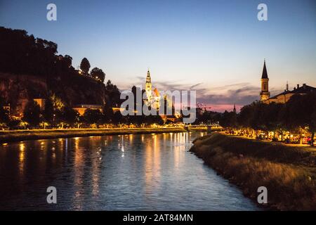 Salzbourg Autriche scène nocturne avec des lumières réfléchis sur la rivière Salzach avec deux églises au crépuscule. Banque D'Images