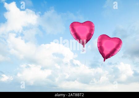 Deux ballons rouges sur fond de nuages de ciel bleu. Beau paysage avec nuages sur le ciel Banque D'Images