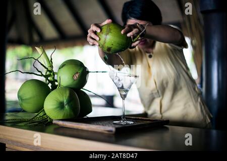 Un barman mélangeant un martini (Praow-Tini) d'un shaker de noix de coco. Banque D'Images