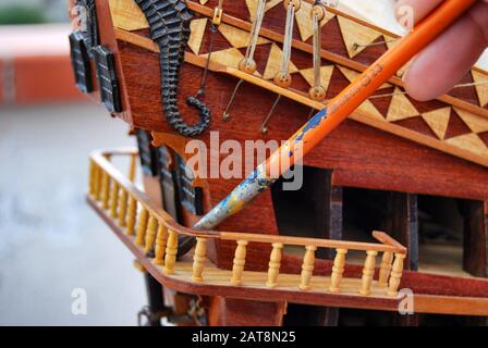 Jeune homme construisant un modèle de navire dans un studio de modélisation de navire - détail de peinture Banque D'Images