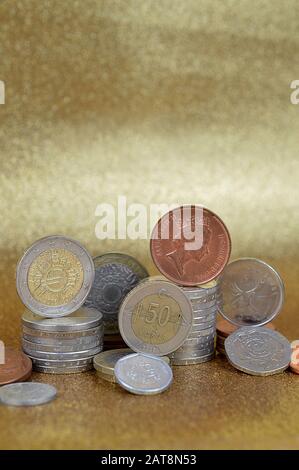 Piles de pièces de différentes nations avec euros et Cents devant le fond doré avec espace de copie ci-dessus Banque D'Images