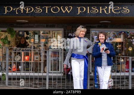 Deux femmes portant des rubans bleus à l'extérieur de Padstow Piskies lors de la procession d'He Obby Oss, Padstow, Cornwall, Royaume-Uni Banque D'Images