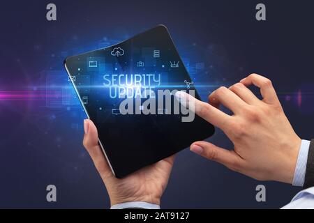 Businessman holding a smartphone pliable avec inscription MISE À JOUR DE SÉCURITÉ, cyber security concept