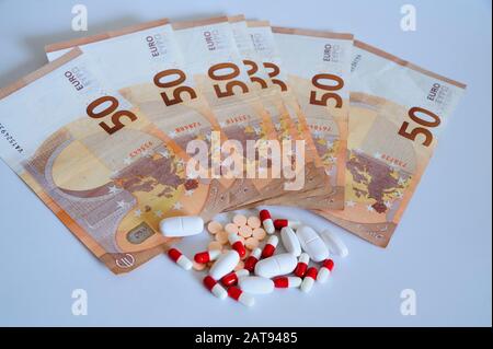 Beaucoup de médicaments en comprimés et en comprimés à côté de cinquante euros de billets de banque sur la surface blanche. Banque D'Images