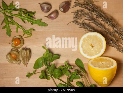 physalis, menthe, citron, arugula, ail et romarin sur une planche en bois Banque D'Images