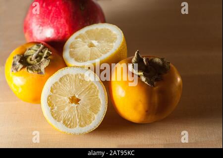 grenade, citron et persimmon sur une planche en bois Banque D'Images