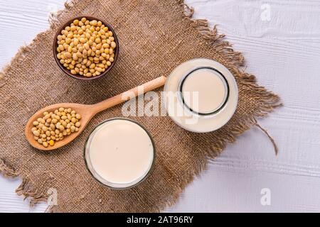 Vue de dessus de la bouteille de lait de soja avec soja sur la table blanche Banque D'Images