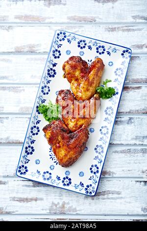 Ailes de poulet épicées aux herbes fraîches. Vue de dessus. Fond en bois clair. Vue de dessus. Banque D'Images