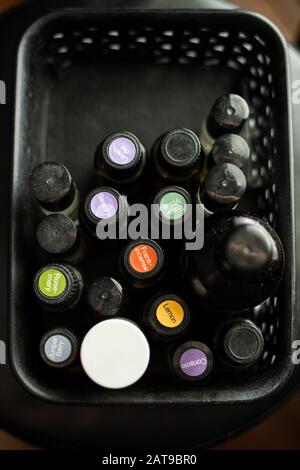 Gros plan faire l'appoint de couvercles de bouteilles en verre noir et blanc d'huiles essentielles étiquetées dans un bac noir Banque D'Images