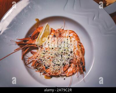 Grandes crevettes tigrées grillées à l'ail, au citron et aux herbes sur une grande plaque blanche. Banque D'Images