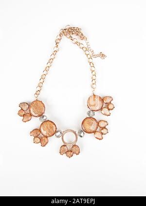 Collier de bijoux en or rose isolé sur fond clair. La chaîne délicate de cet accessoire de mode est dotée de pierres précieuses en cuivre. Banque D'Images