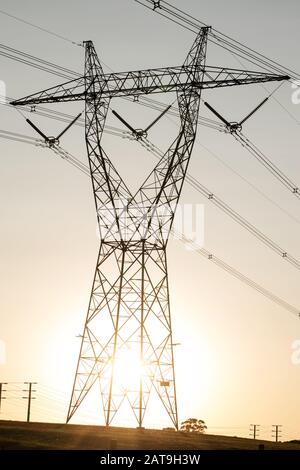 Paysage de lignes électriques australiennes haute tension avec coucher de soleil derrière Banque D'Images