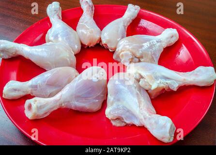 Une bande de morceaux de poulet cru dans une plaque rouge, prête à frire. Banque D'Images