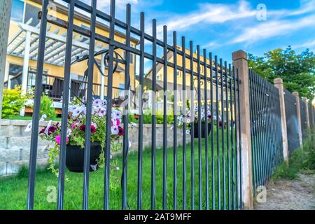 Clôture en métal noir avec fleurs en pot colorées contre les maisons floues et le ciel bleu Banque D'Images