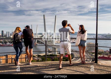 Les touristes prennent des photos avec vue sur le Golden Bridge construit de l'autre côté de la baie de la Corne d'Or à Vladivostok Banque D'Images