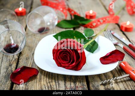 La rose sur la plaque, deux vitivinicoles, corkscrew, couteau, fourche et bougies brûlantes sur une vieille table en bois. Mise au point sélective. Banque D'Images