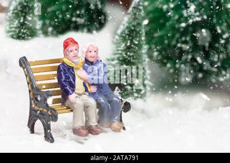 Les figurines miniatures du conjoint sont assis sur des bancs. Couple de personnes âgées en hiver à l'extérieur Banque D'Images