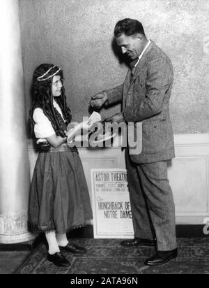 Lon CHANEY achetant des billets pour une performance de bénéfice d'une jeune fille vêtue comme Esmeralda au Astor Theatre New York le jeudi 6 septembre du HUNCHBACK DE NOTRE DAME 1923 réalisateur WALLACE WORSLEY roman Victor Hugo Silent Movie Universal Pictures Banque D'Images