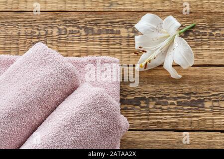 Serviettes douces en éponge avec fleur de lys blanche sur les vieux panneaux en bois. Vue de dessus. Banque D'Images