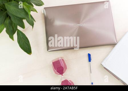 Freelance. Travailler à la maison. Le concept de la répartition du temps au travail. Gestion du temps. HourGlass, ordinateur portable et ordinateur portable sur une table blanche. Banque D'Images