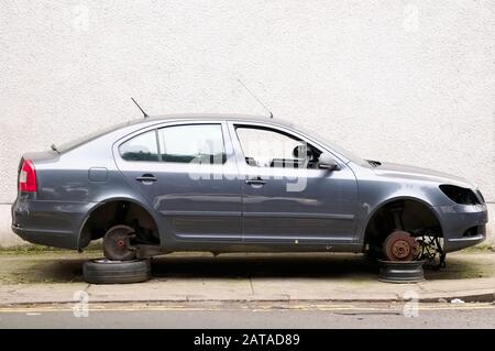 Voiture avec roues volées pour la réparation au garage levé sur des briques Banque D'Images