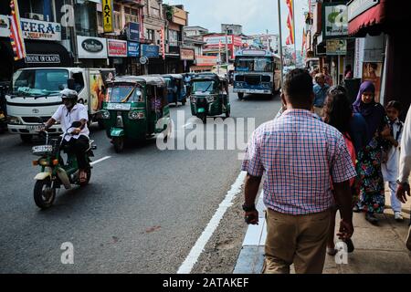 La vie dans la rue au Sri Lanka, les gens marchant sur le trottoir, tandis que la circulation continue. Vélos, Tuk tuk, bus... Banque D'Images