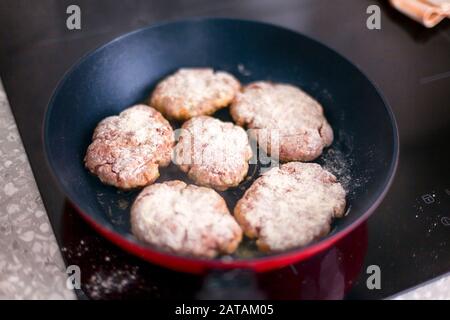 Côtelettes maison dans la cuisson de poêle sur table de cuisson à induction. Gros plan. Banque D'Images