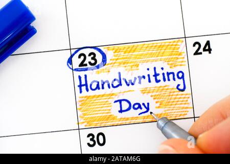Femme doigts avec stylo écriture rappel Handwriting jour dans le calendrier. 23 Janvier. Banque D'Images