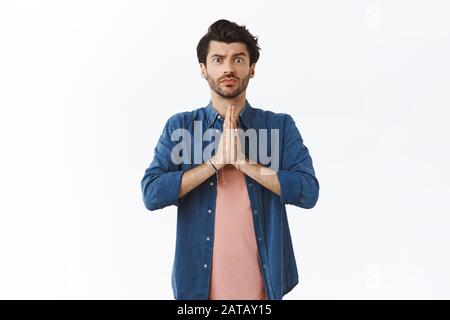 Guy supplie pour la faveur, a besoin de votre aide asap. L'homme barbu intense et sérieux se tient les mains enfoncées près de la poitrine dans le geste de prière, comme le clin d'œil Banque D'Images