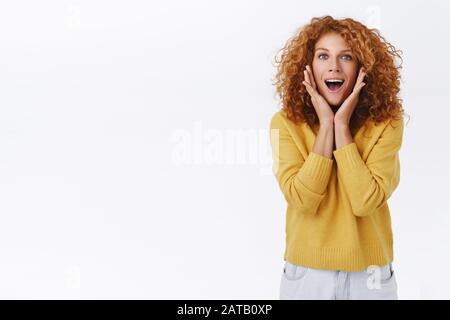 Excitée, amusante, belle-femme blanche à tête rouge avec des cheveux frisés, look demandé et étonnée, fasciné par la bouche ouverte dire wow, touch Banque D'Images