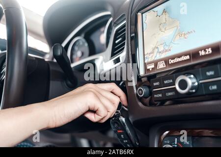 Mode de transport. Une femme de gros plan à l'intérieur de la voiture électrique tenant la clé de la voiture de démarrage Banque D'Images