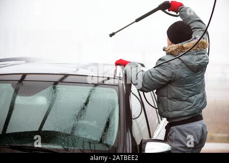 Homme laver sa voiture sous l'eau haute pression à l'extérieur. - Image Banque D'Images