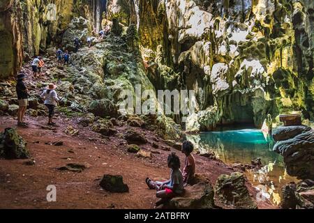 Locaux dans une grotte d'eau saumâtre sur l'île de Panasia, Papouasie-Nouvelle-Guinée. Avec soin, un groupe se sent au fond de la caverne naturelle Banque D'Images