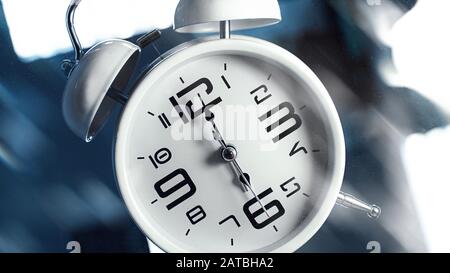Réveil blanc sur fond bleu éclairé. Il est six heures. Concept de réveil Banque D'Images