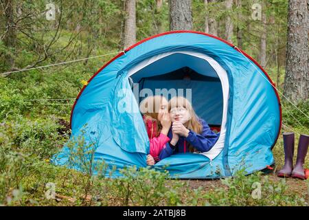 Les filles Tween partagent un secret ou commérages mentant ensemble dans la tente tout en campant dans une forêt d'été pendant les vacances d'été Banque D'Images