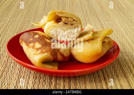 Les crêpes avec farce de fromage blanc sur la plaque rouge. Repas matinal Matutinal à partir de produits laitiers Banque D'Images