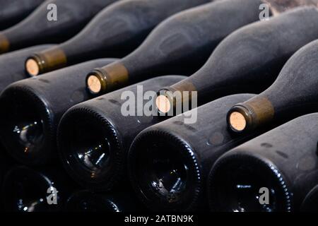 Des piles de bouteilles de vin dans des casiers à plat dans la vieille cave à vin ou cave. Vault Concept avec de vieux vins rares, collection exclusive. Des bouteilles de vin antique Banque D'Images