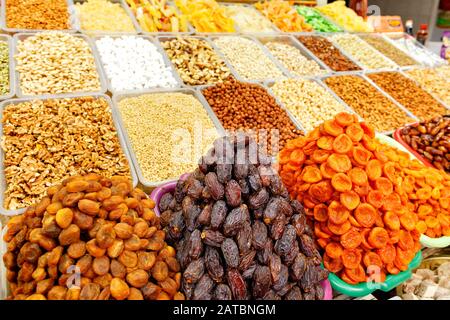 Les lames avec dattes, abricots secs, amandes, noisettes, noix, noix de cajou en flou sont vendues sur les étagères du marché oriental. Banque D'Images