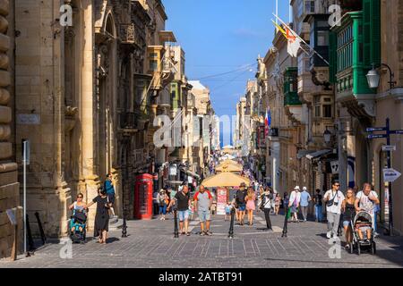 Valletta, Malte - 13 octobre 2019: Rue des marchands dans la capitale, rue commerçante animée avec des touristes et des habitants, des étals, des magasins Banque D'Images