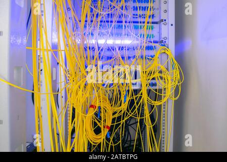 Les fils de lot sont connectés dans le cadre de distribution de fibre optique. Les câbles désordonnés sont reliés dans le rack de la salle de serveurs. Les fils à fibres optiques sont situés Banque D'Images