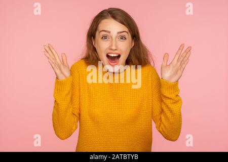 WOW, oh mon dieu! Portrait de la jeune fille de gingembre enchantée dans le sweat-shirt levant les mains et regardant la caméra avec étonnement, choqué par un succès inattendu Banque D'Images