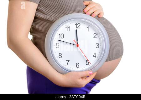 Pregnant woman holding wall clock. C'est le temps. Isolé sur blanc. Banque D'Images