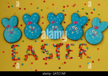 Pâques lapins bleus drôles, biscuits faits maison au pain d'épices peints en glacer sur un fond jaune Banque D'Images