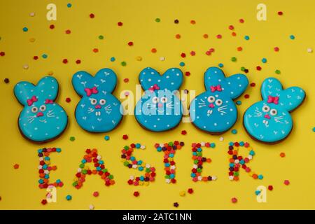 Pâques lapins bleus drôles, biscuits faits maison au pain d'épices peints en glacer sur un fond jaune Banque D'Images