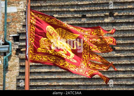 Drapeau de Venise se vengeant dans la rue à Venise, Italie. Lion ailé d'or sur le drapeau rouge, vue rapprochée. Le vieux drapeau vénitien est sur le fond de la maison de millésime wa Banque D'Images