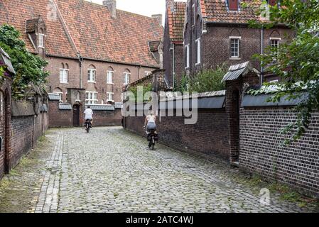 Gand, Flandre / Belgique - 09 02 2019:couple d'âge moyen conduisant la bicyclette au beguinage de Saint Elisabeth et Saint Amandsberg Banque D'Images